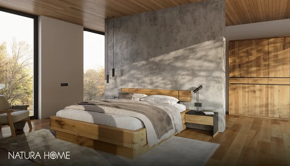 Stilvolles NATURA HOME Schlafzimmer mit Massivholzbett, Bettnachttischen und Schrank in warmem Holz, kombiniert mit Betondekorwand und großen Fenstern für natürliche, moderne Raumgestaltung.